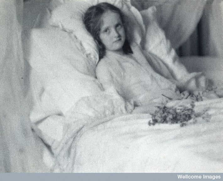 L0028326 A convalescent girl, lying in bed, holding a bunch of flower